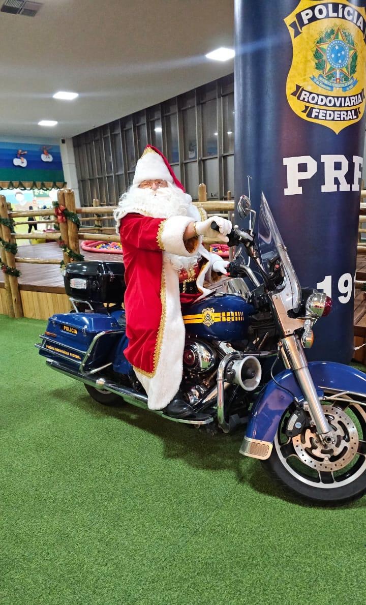 Papai Noel sentado na motocicleta da PRF em evento natalino