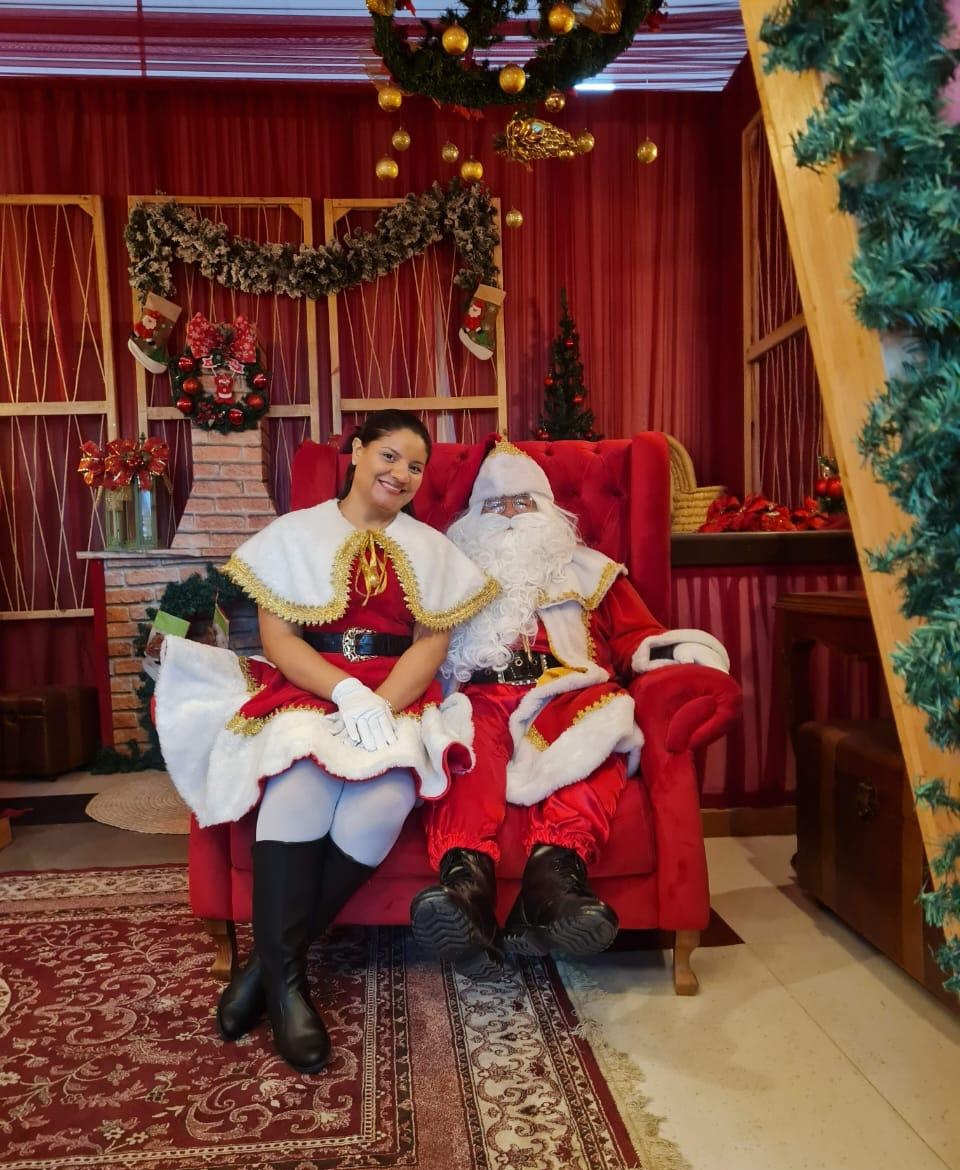 Papai Noel e Noelete sentados na poltrona em ambiente natalino